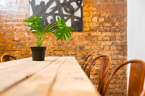 A wooden table with a potted plant in the center, surrounded by chairs.