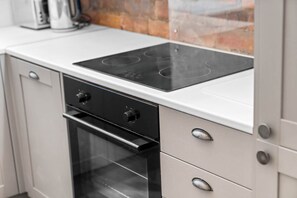 A kitchen with a black induction cooktop, a stainless steel oven, and a white countertop. - Stylish 2 Bedroom Apartment - Netflix - Wolverhampton Centre (Wolverhampton)