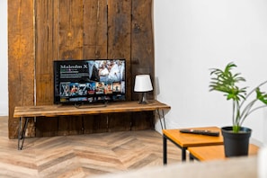 A television on a wooden stand displaying a movie selection screen. - Stylish 2 Bedroom Apartment - Netflix - Wolverhampton Centre (Wolverhampton)