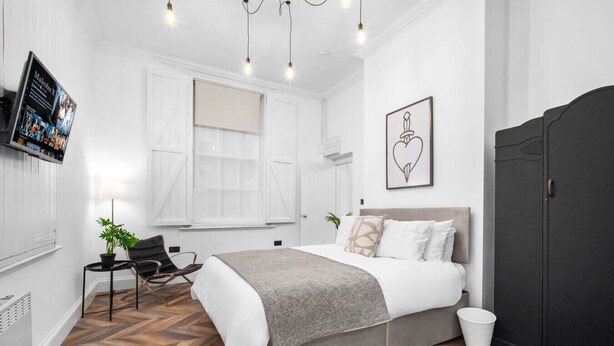 Ein modernes Schlafzimmer mit Bett, Schreibtisch, Stuhl und Kleiderschrank.