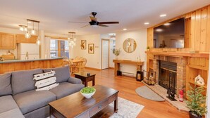 A spacious living room with a gray sofa, wooden coffee table, and a fireplace. - Deer Park-Shuttle-Amenities- Fireplace (Woodstock)