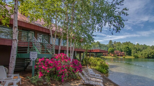 A lakeside hotel with a covered walkway, outdoor seating, and a sign warning of no lifeguard on duty. - Deer Park-Shuttle-Amenities- Fireplace (Woodstock)
