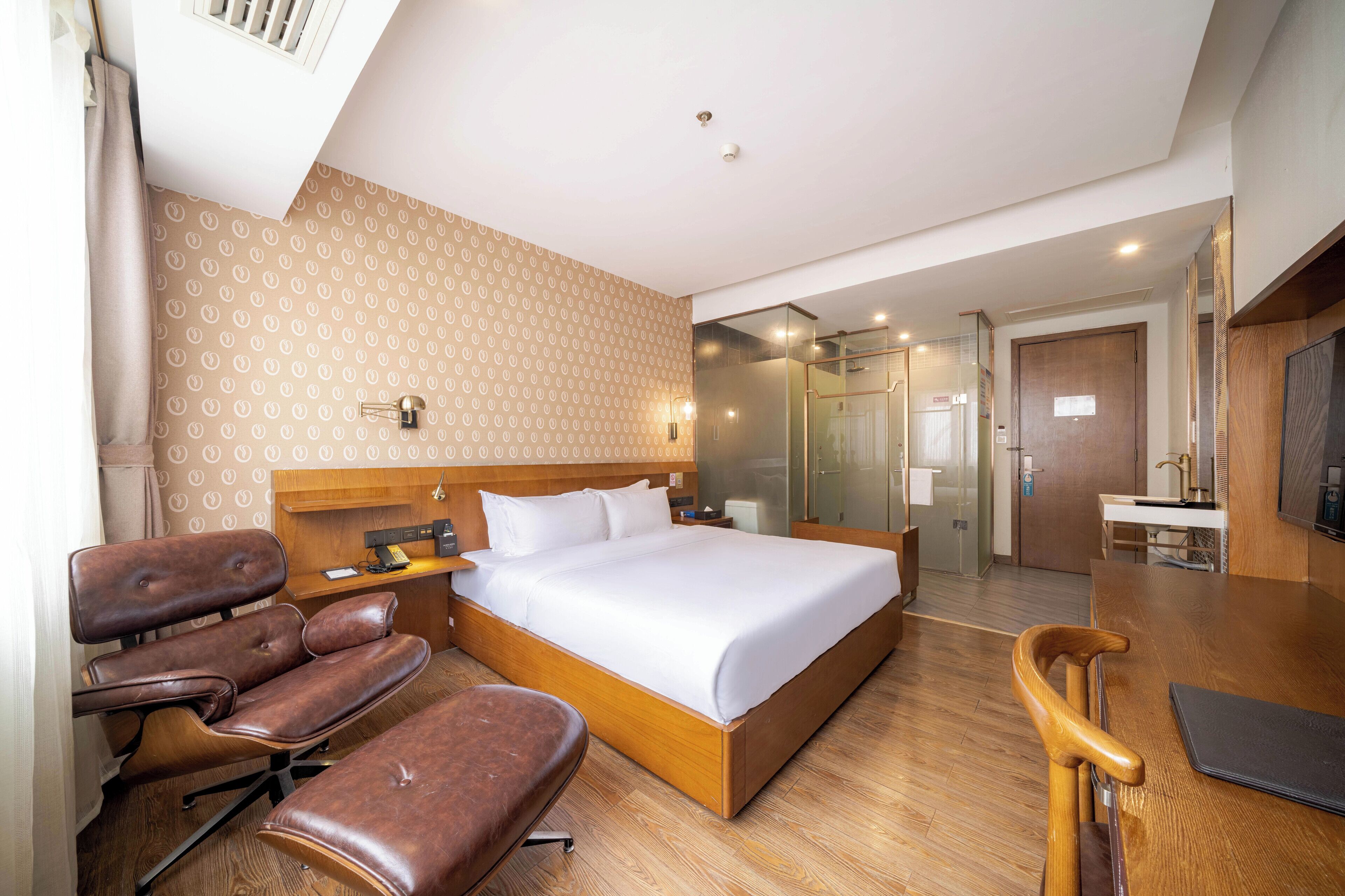 A hotel room with a large bed, a wooden desk, a chair, and a TV.