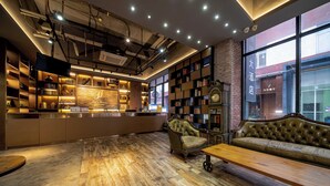 A cozy library with bookshelves, a leather armchair, and a wooden bench. - Xingyi Chain Hotel Jiangxia Metro Station (Guangzhou)
