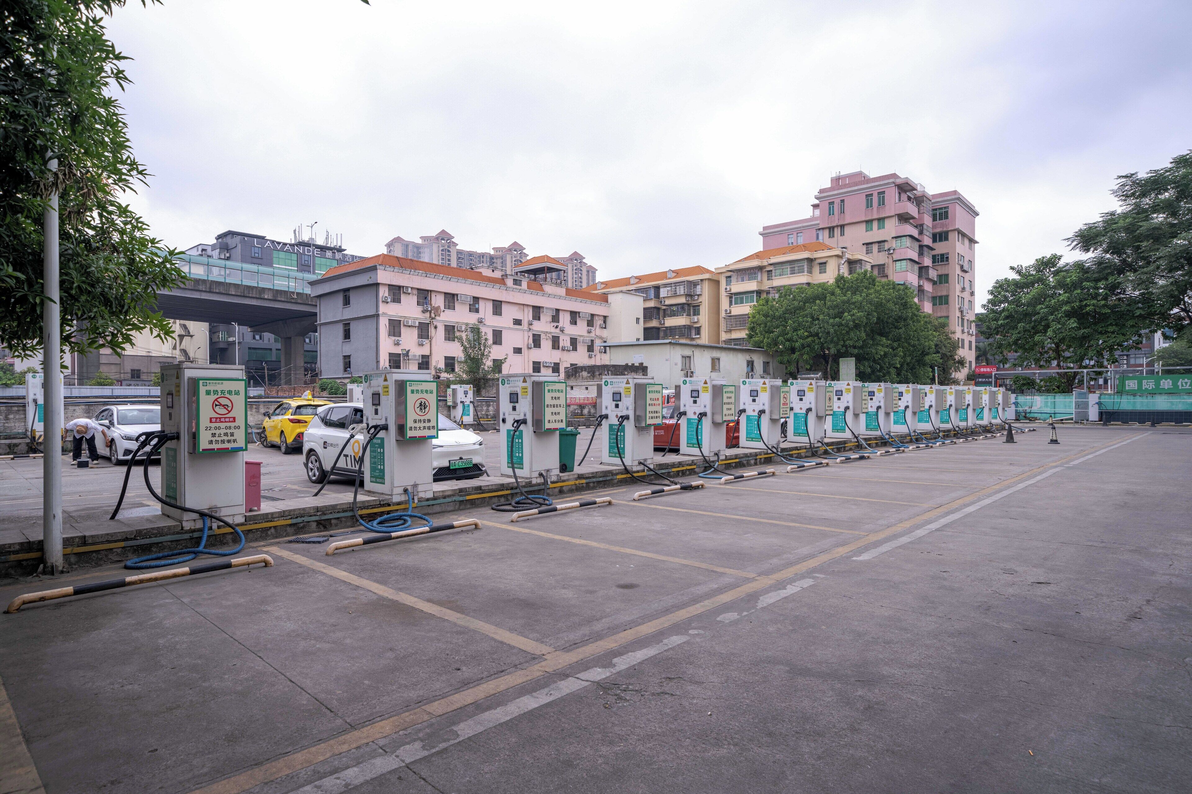 A parking area with multiple fuel pumps, a white car, and a yellow car.