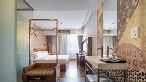 A modern hotel room with a large bed, a wooden bench, a desk, and a bathroom with a tiled wall. - Xingyi Chain Hotel Jiangxia Metro Station (Guangzhou)
