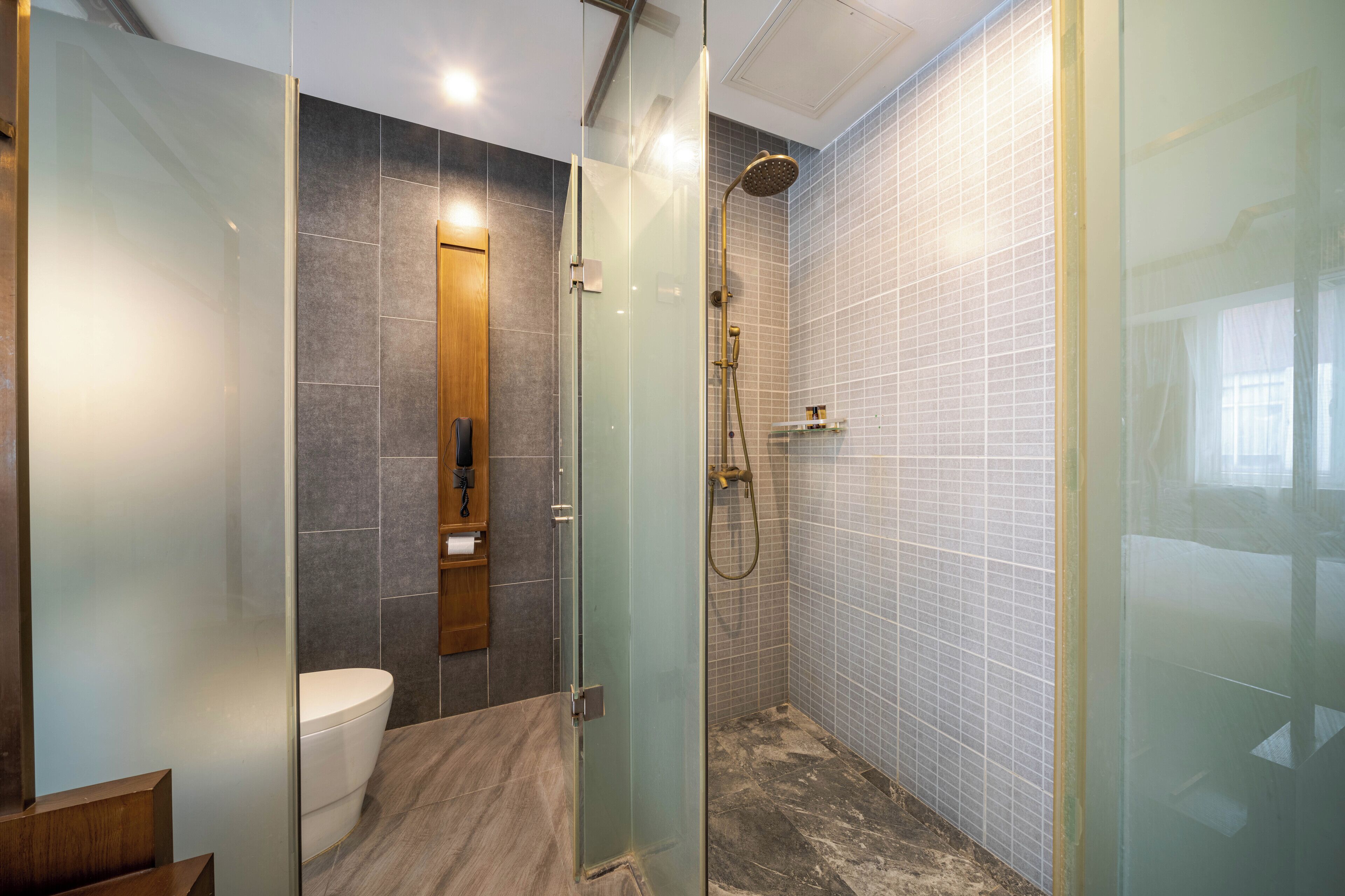 Un baño moderno con ducha envuelta en vidrio, inodoro y tocador de madera.