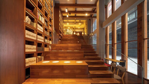 A staircase with wooden steps leading to a reading area with bookshelves and tables. - Xingyi Chain Hotel Jiangxia Metro Station (Guangzhou)