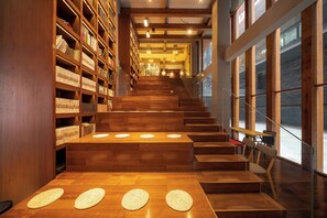 Una escalera de madera conduce a un espacio de lectura con estanterías y mesas.
