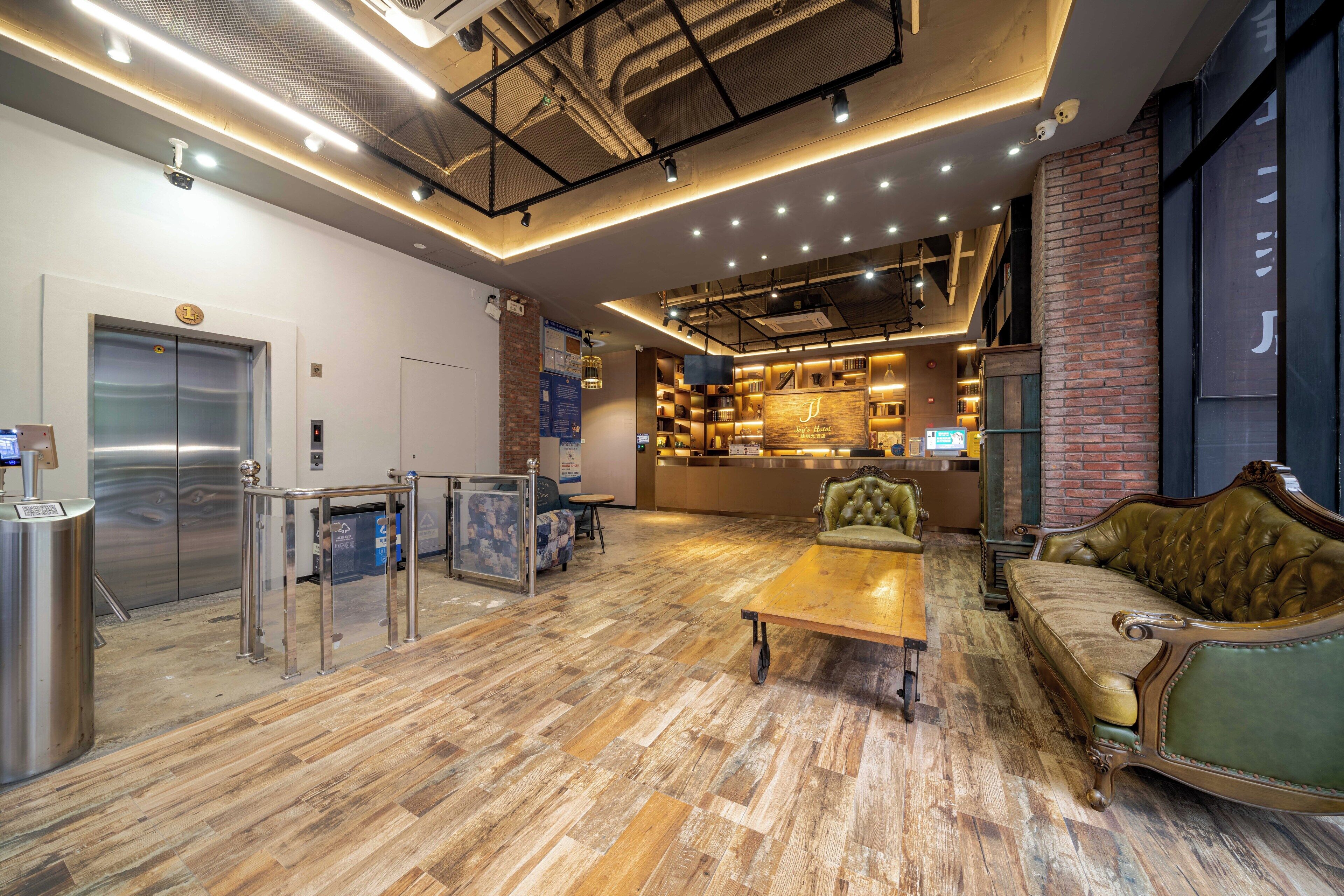 A lobby with a wooden floor, a reception desk, a green sofa, and a bar area.