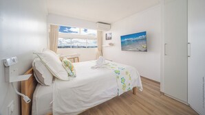 Hotelkamer met een bed, een raam met uitzicht over de stad, een airconditioning en een schilderij aan de muur.