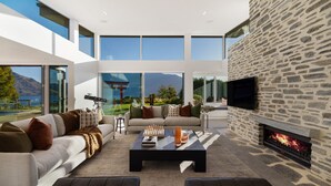 A modern living room with a stone wall, a fireplace, and large windows overlooking a scenic landscape.