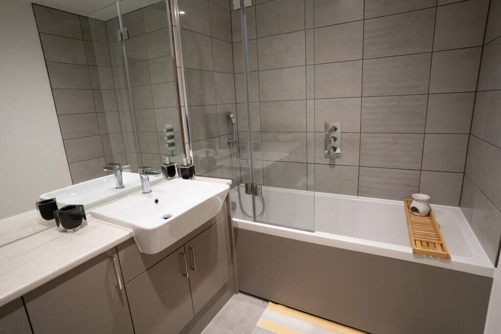 A modern bathroom with two sinks, a glass shower enclosure, and a bathtub.