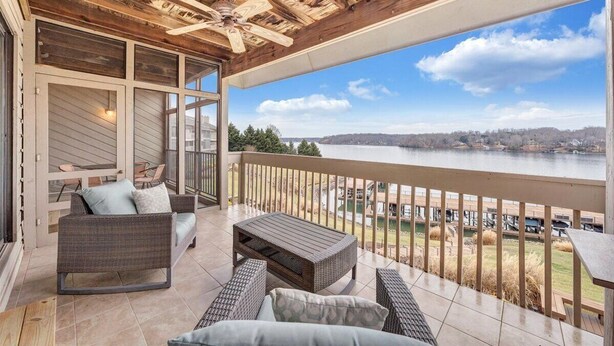 Ein Balkon mit Korbmöbeln, einem Deckenventilator und Blick auf einen See.