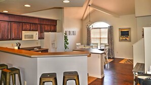 A spacious kitchen with dark wood cabinets, a white refrigerator, and a built-in microwave. There is a central island with stools, and a dining area with a table and chairs. - SPACIOUS GOLF Course view & close to Strip, Lake & SDC! BEST LOCATION in town!  (Branson)