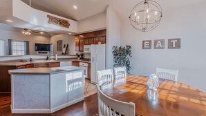 A modern kitchen with a central island, wooden cabinets, and a dining area with a round table and chairs. - SPACIOUS GOLF Course view & close to Strip, Lake & SDC! BEST LOCATION in town!  (Branson)