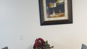 A dining table with a framed picture, a vase with flowers, and a welcome card. - Elite 2-bedroom apartment in Moose Creek with WiFi (North Pole)