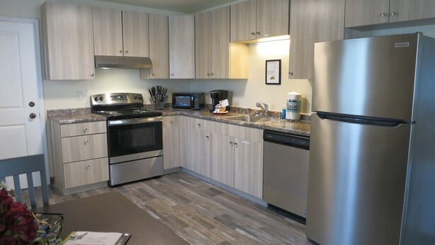 A modern kitchen with stainless steel appliances, wooden cabinets, and a granite countertop. - Elite 2-bedroom apartment in Moose Creek with WiFi (North Pole)