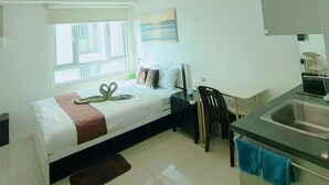 A modern bedroom with a bed, bedside table, and a window. - The Catalina Suite at The Beacon Makati (Makati)