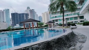 A swimming pool with a stone-lined edge, surrounded by a modern building with multiple floors and balconies. - The Catalina Suite at The Beacon Makati (Makati)