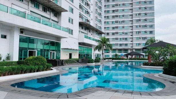 A swimming pool surrounded by modern buildings with balconies and large windows. - The Catalina Suite at The Beacon Makati (Makati)