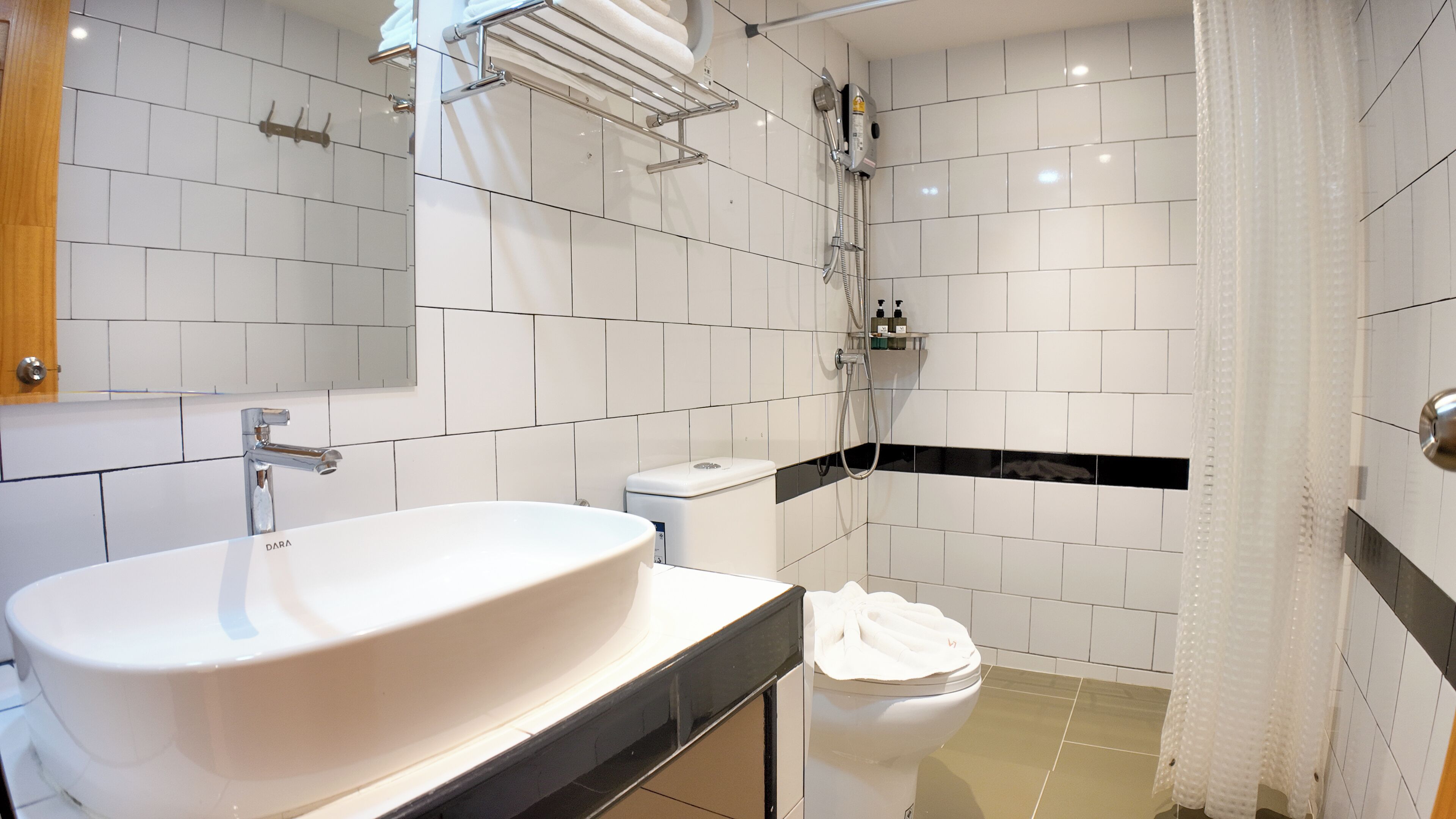 A modern bathroom with a large white sink, a toilet, and a shower area.