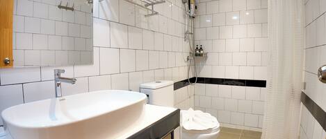 A modern bathroom with a large white sink, a toilet, and a shower area.