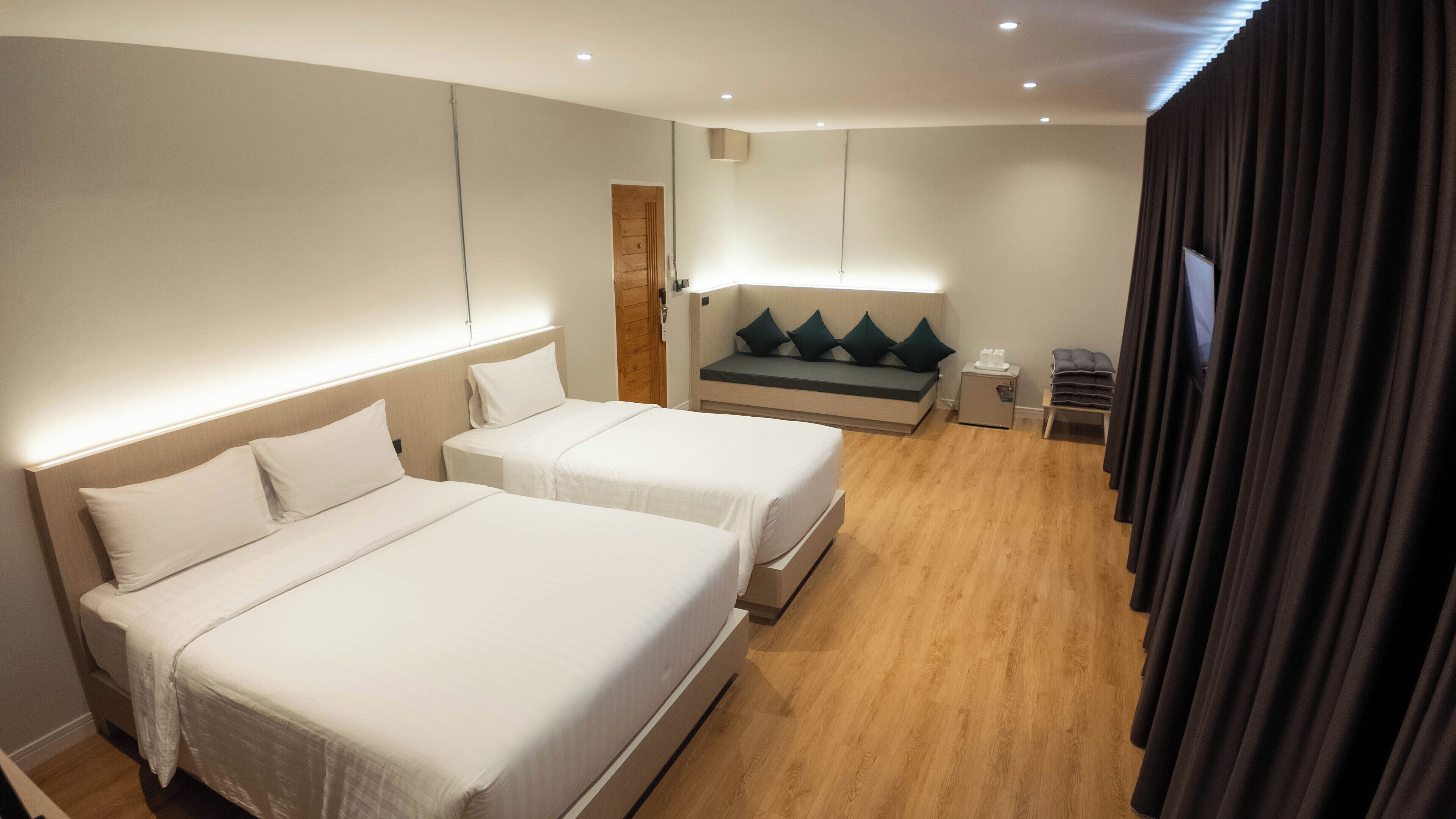 Une chambre d’hôtel avec deux lits, un canapé, une petite table et un téléviseur.