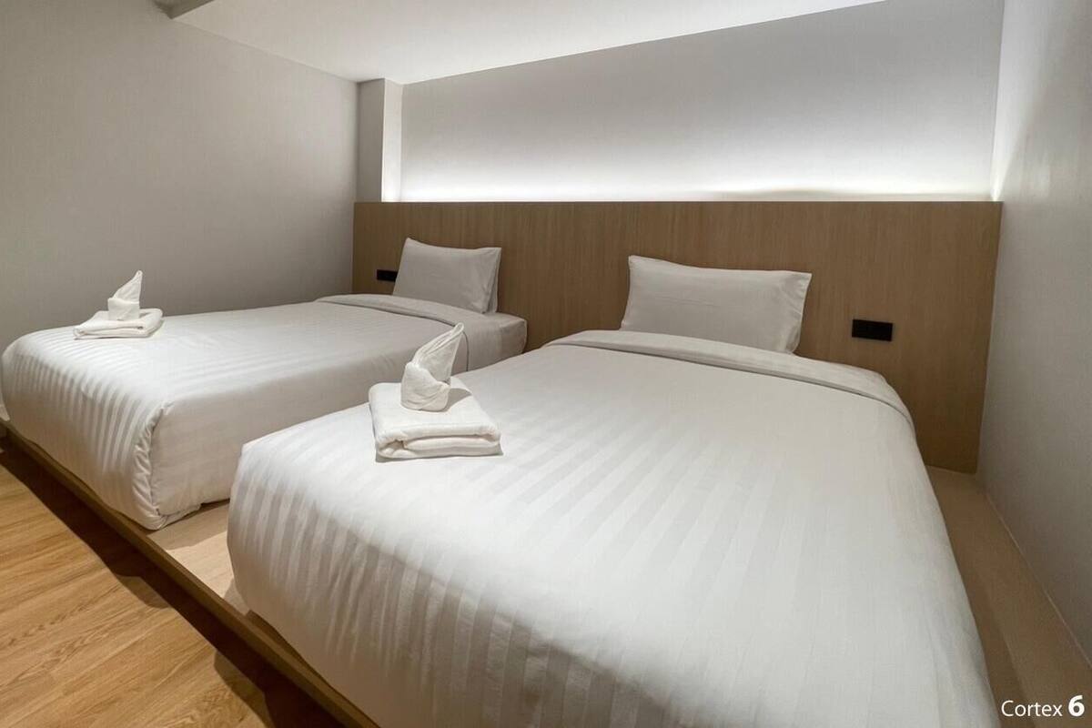 A hotel room with two beds, each with a wooden headboard and white bedding.
