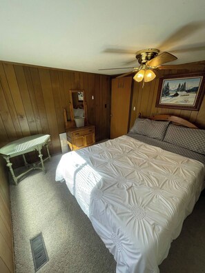 A bedroom with a large bed, a wooden dresser, a bench, and a ceiling fan. - Secluded Colorado Ranch on 140 Acres Near Salida (Cotopaxi)