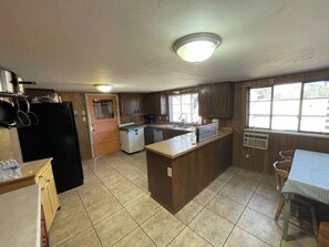 A compact kitchen with a central island, a refrigerator, and a window providing natural light. - Secluded Colorado Ranch on 140 Acres Near Salida (Cotopaxi)