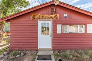 A red wooden building with a white door, a small window, and a sign above the door. - Secluded Colorado Ranch on 140 Acres Near Salida (Cotopaxi)