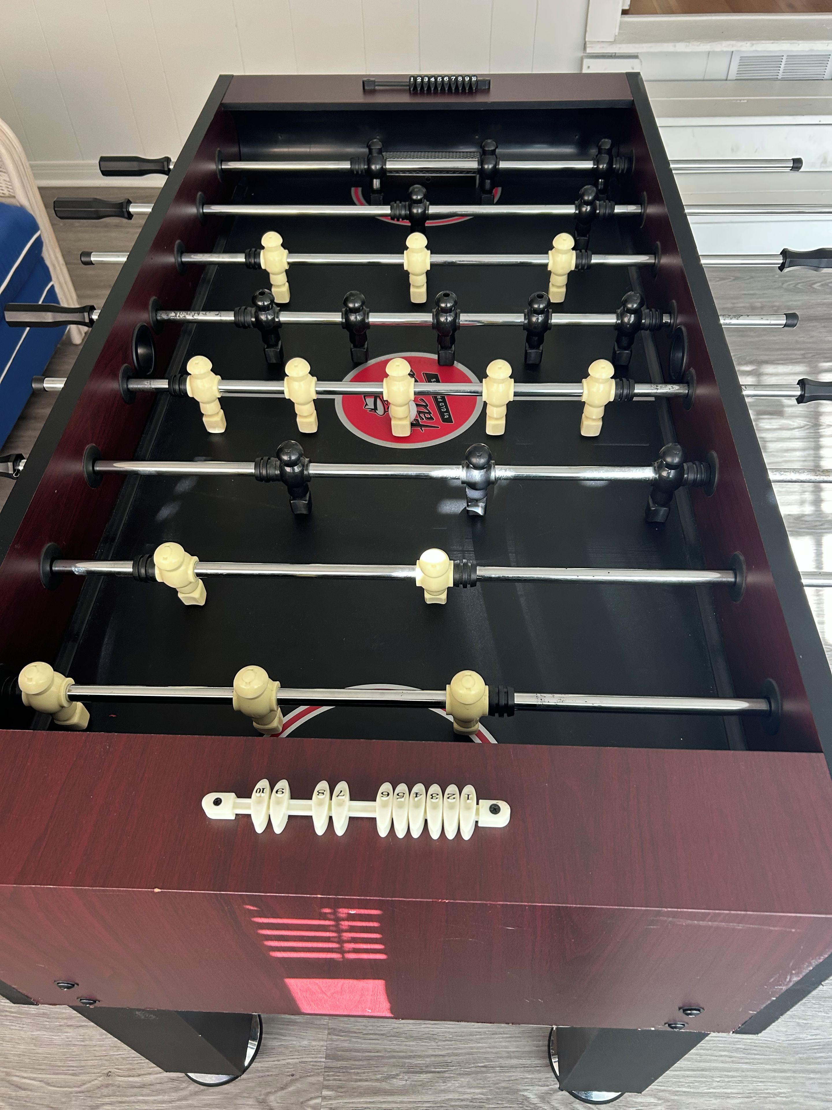 A foosball table with a red and black color scheme, featuring a logo in the center.