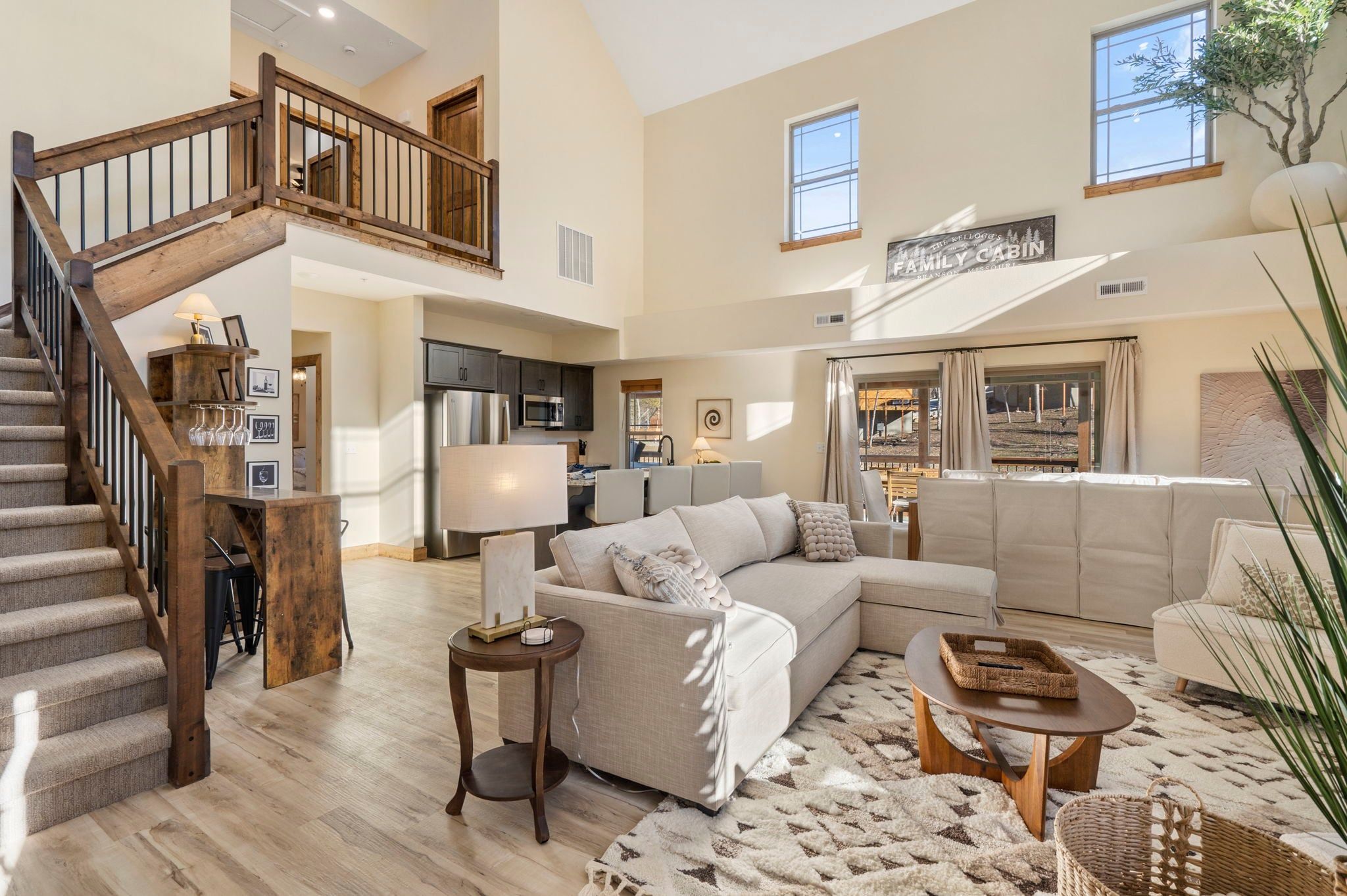 A spacious living area with a staircase, a kitchen, and a large window.