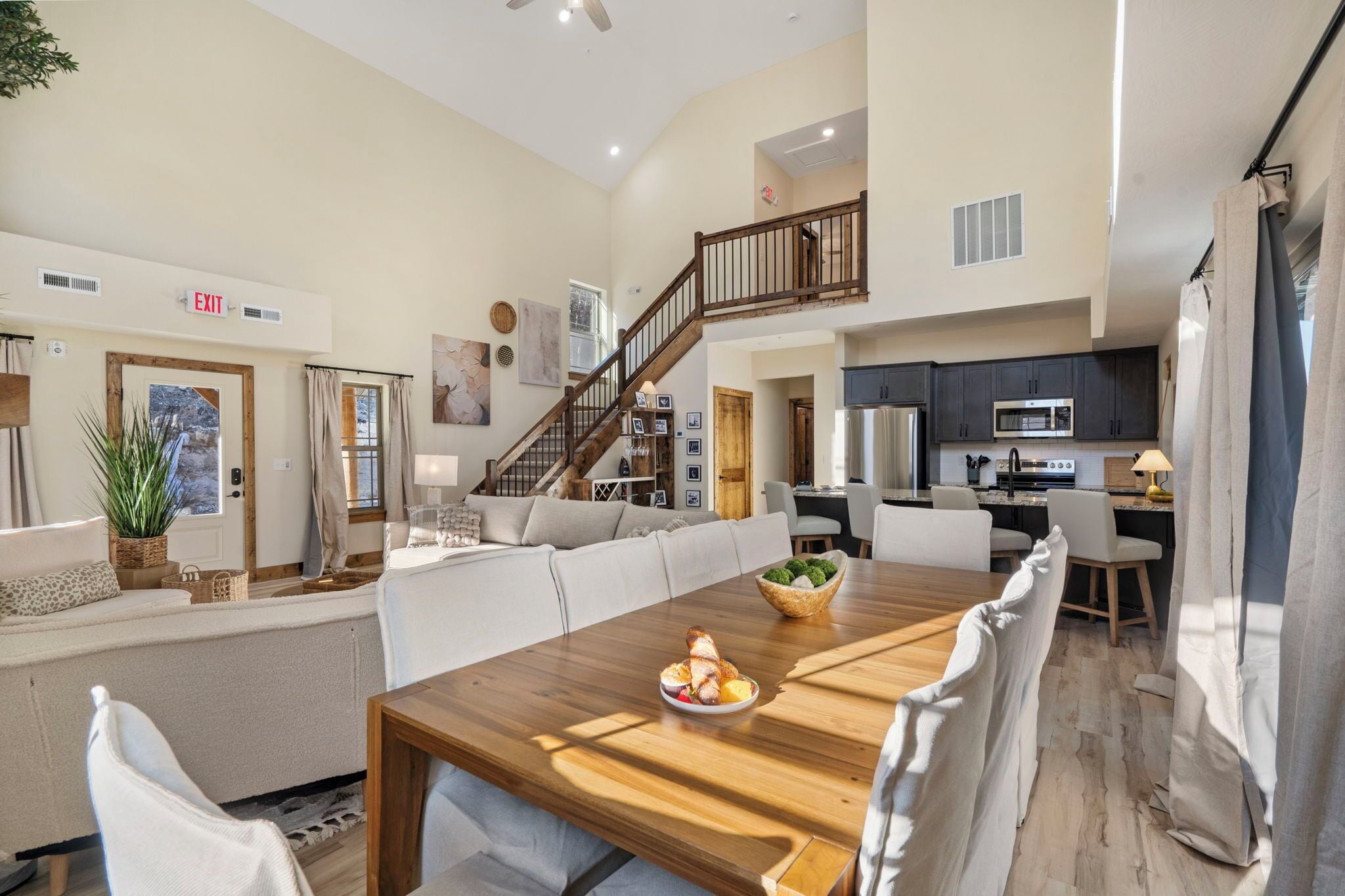Un espacio habitable amplio con una mesa de comedor de madera, un sofá y una escalera que sube a un nivel superior.