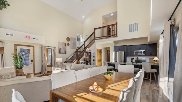 Un espacio habitable amplio con una mesa de comedor de madera, un sofá y una escalera que sube a un nivel superior.