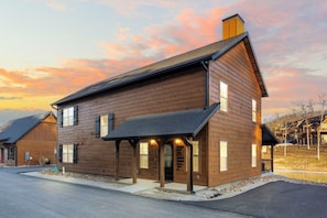 A two-story wooden house with a covered porch, a chimney, and a garage.
