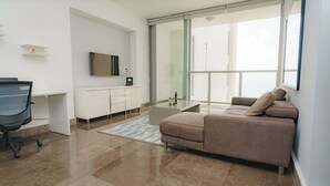 A modern bedroom with a large bed, a desk, a chair, and a TV.