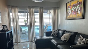 A modern living room with a black leather sofa, a grey armchair, and a framed artwork on the wall. - Charming 3-bedroom apartment with WiFi, AC and a picuzzy in Santo Domingo Oeste. (Santo Domingo Oeste)