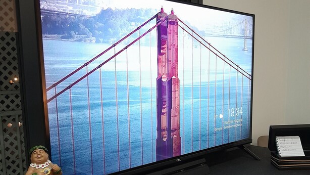 Een televisie waarop de Golden Gate Bridge te zien is, een klein beeldje en een decoratieve doos op een bureau.