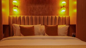 A hotel room with a large bed, two wall-mounted lamps, and a geometric patterned wall. - Romantic Dream Arch View (Cabo San Lucas)