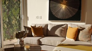 A modern living room with a beige sofa, a round coffee table, and a large abstract painting on the wall. - Romantic Dream Arch View (Cabo San Lucas)