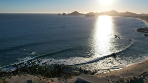 A coastal landscape with a beach, rocky shoreline, and distant mountains. - Romantic Dream Arch View (Cabo San Lucas)