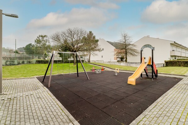 Un parque infantil con columpios, tobogán y sube y baja.