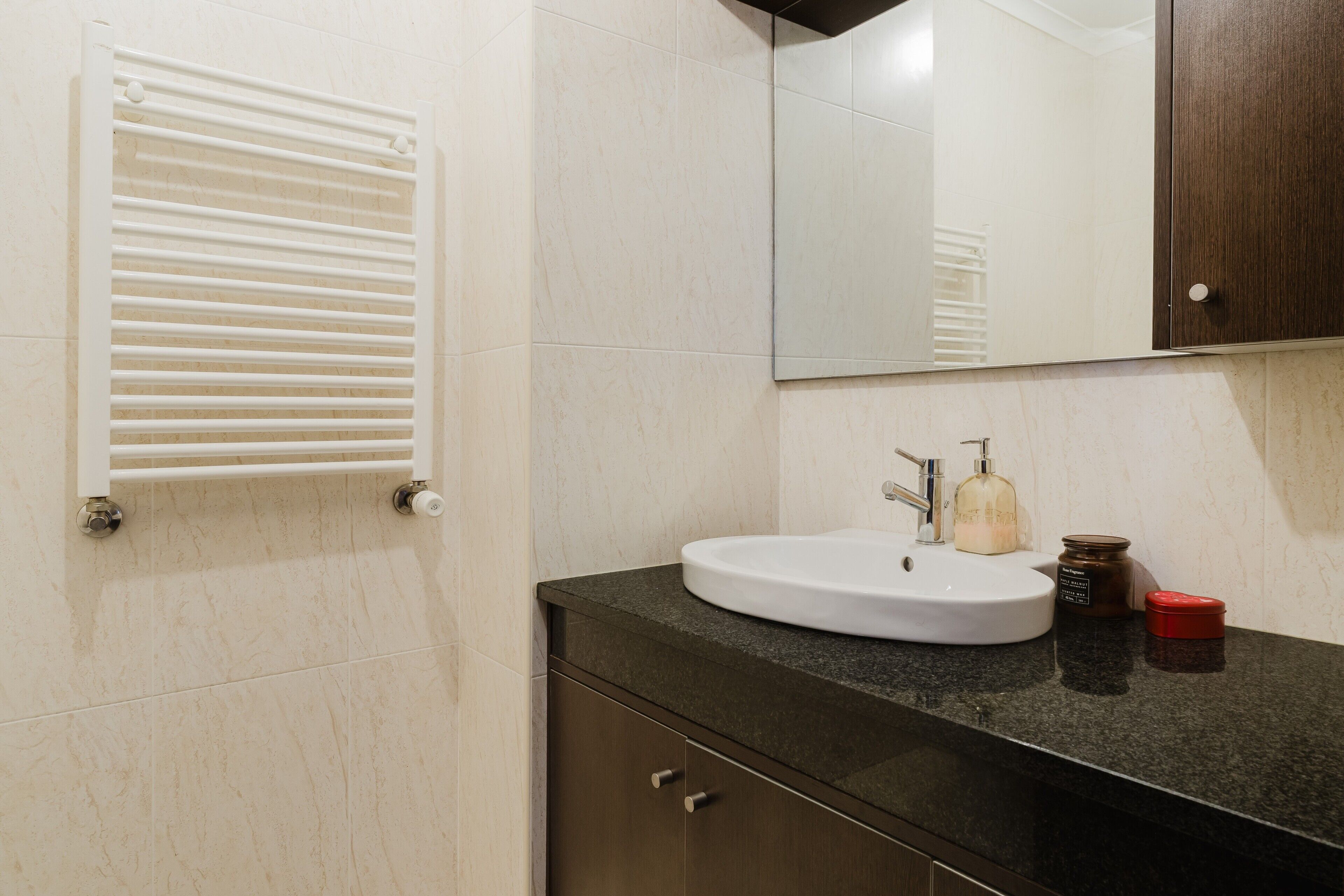 A bathroom with a white sink, dark countertop, and a mirror above it.