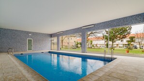 Ein beheizter Innenpool mit gefliesten Wänden und Blick ins Freie.