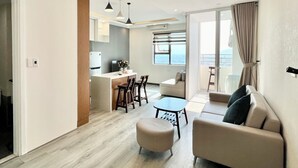 Un salon moderne avec un canapé, un pouf et un coin repas comprenant des chaises.