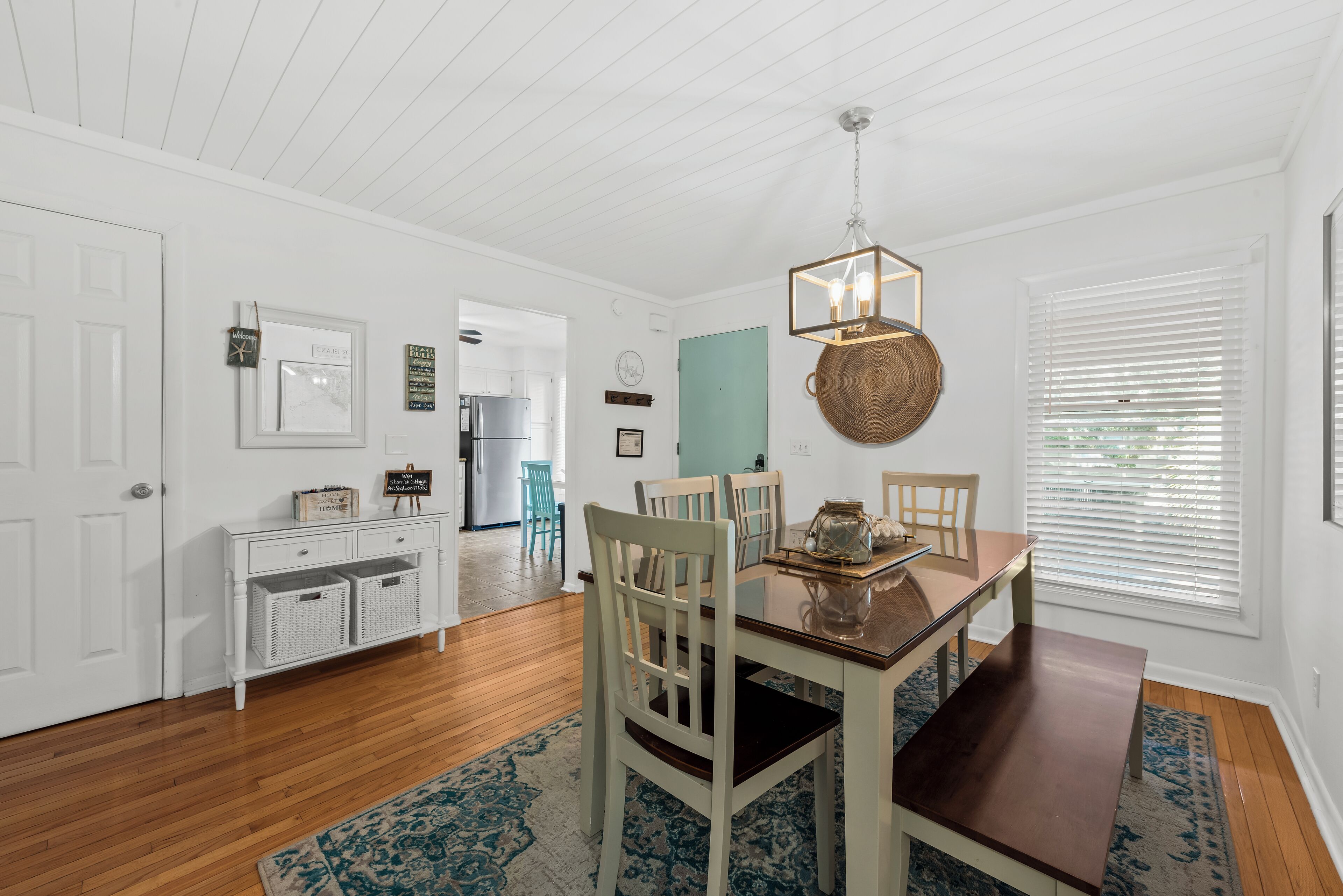 A dining area with a wooden table, chairs, and a hanging light fixture.