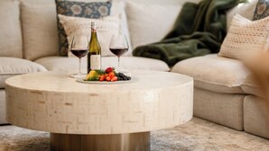 Ein runder Tisch mit gewebtem Muster, zwei Weinflaschen und ein Glas Rotwein.