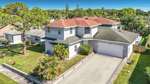 A two-story house with a red roof, a garage, and a well-maintained lawn.